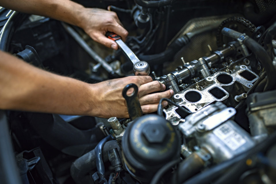 Car mechanic at a garage fixing an engine.