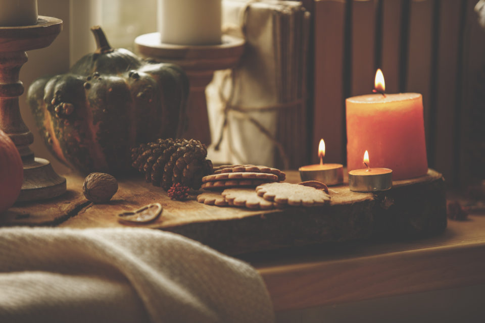 Close-up of still life composition of lit candles, cookies and pumpkin set up on a wooden table