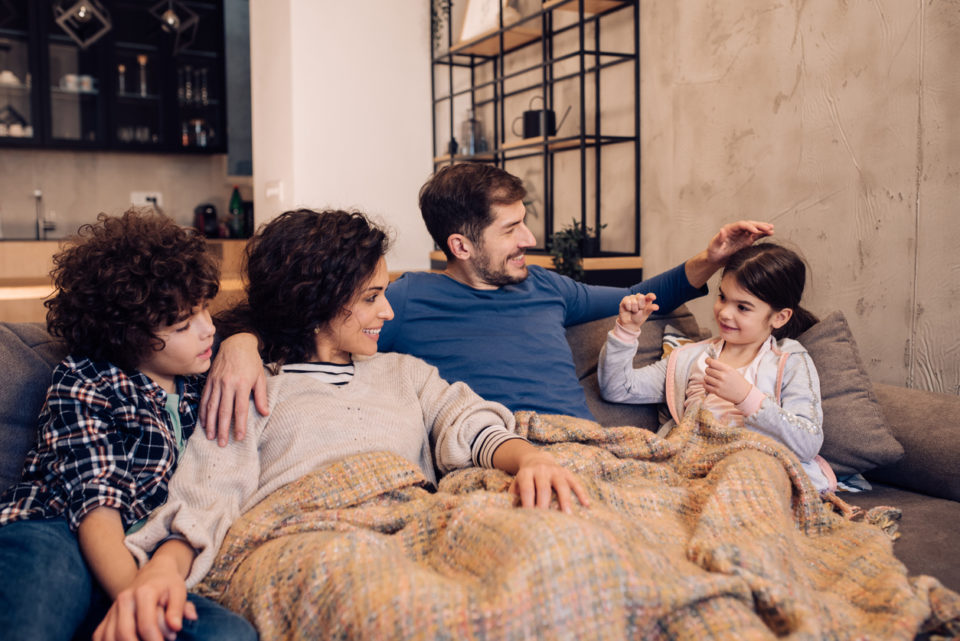 Young couple and their two children relaxing on the couch.