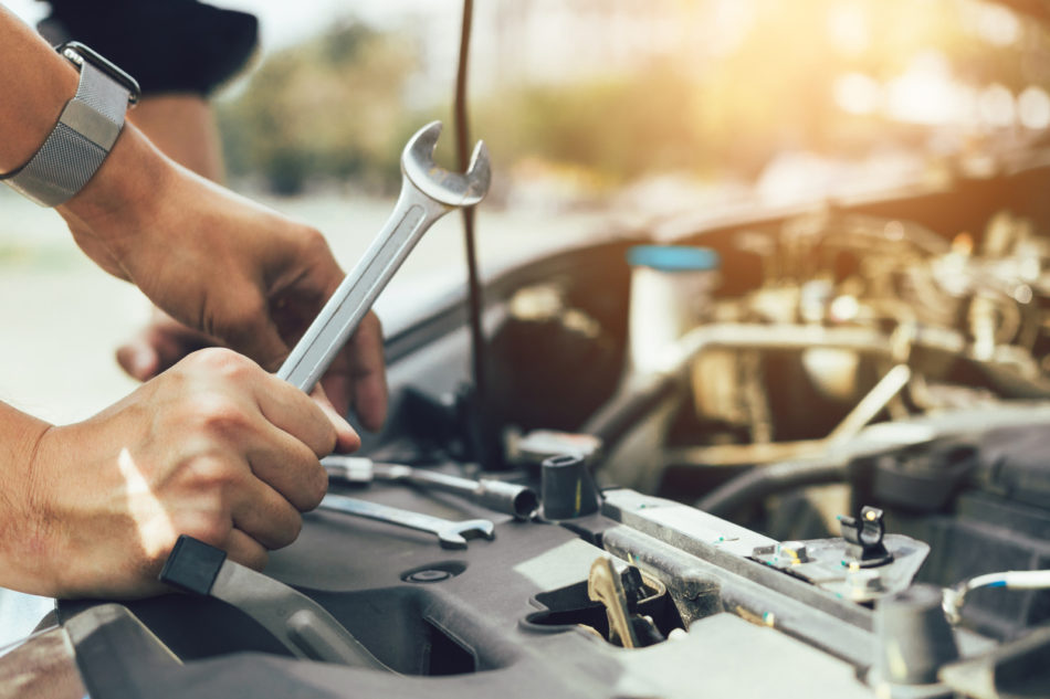 Car mechanic is holding a wrench ready to check the engine