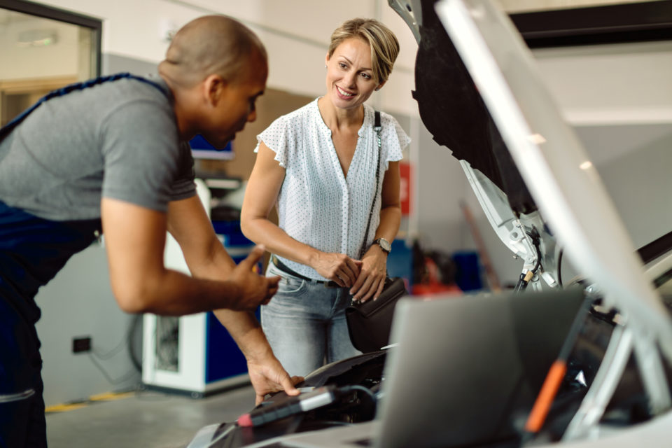 Happy woman talking to her car mechanic