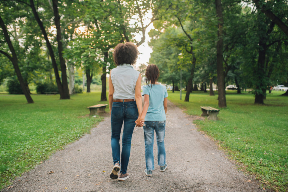 Young woman and young girls holding hands and walking away