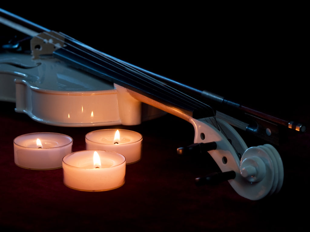 Close-up of a white violin with three Candle.