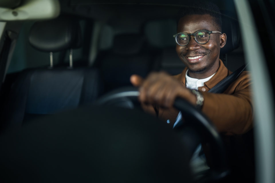 Cheerful young man enjoys driving his car.