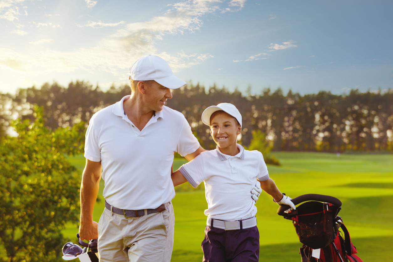 man with his son golfers walking on golf course