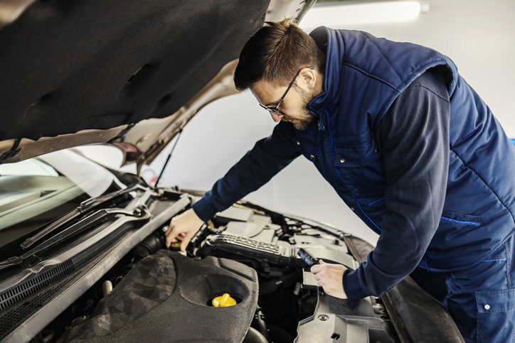 An auto mechanic repairing car engine in garage.