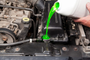 A mechanic is pouring antifreeze into a vehicle's radiator.